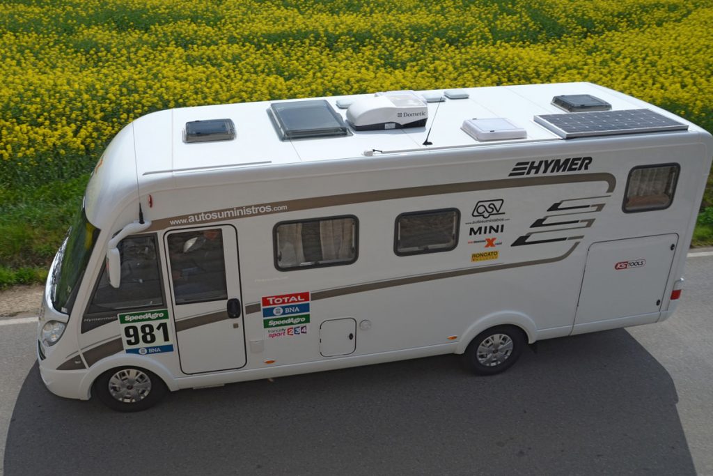 Disponer de un panel solar en nuestra autocaravana es un puro ejercicio de lógica. Para empezar, proporciona un plus de energía necesaria cuya obtención, además, resulta limpia y económica. Dos factores que parecen ligados al ocio camper casi desde su propia concepción. Convertir la luz del sol en electricidad es un método ecológico, barato y rápido de disponer de todo tipo de lujos y servicios en nuestro vehículo recreativo. Por ejemplo, con un panel solar de 180W y una batería de 90 o 100ah podemos pasar cómodamente un fin de semana utilizando la televisión, el agua de noche y el agua caliente junto a otros accesorios como el Wifi. Solo habría que cuidar la carga de la batería, disponer de unas condiciones climatológicas medianamente favorables y usar los electrodomésticos con cierta moderación. En definitiva, dar una patada a las compañías eléctricas… Todo parece lógico y fácil, no obstante, el uso de energía solar fotovoltaica en autocaravanas todavía es una gran desconocida en nuestro país. Los recursos más comunes en España son las placas solares monocristalinas o policristalinas de 12v y 24 V, que se diferencian en la mezcla de cristales que la componen (en el primer caso el rendimiento es superior debido al uso de un cristal homogénea). Lo más determinante a la hora de elegir entre uno u otro es el lugar geográfico donde se instalen: los monicristalinos son mejores en países fríos porque resisten menos el sobrecalentamiento. No obstante, el tamaño de la placa y el uso que vayamos a darle puede ser vital a la hora de disponer de u otra. A partir de aquí nosotros modulamos las prestaciones, la capacidad y la potencia de los aparatos montados en nuestro vehículo, así como el uso que vayamos a hacer de ellos. ¿Saldremos en otoño o en verano? ¿Qué autonomía necesitaremos? ¿Disponemos de un medio de transporte eléctrico adicional -como una bici o una moto- que vaya a necesitar carga de batería? Se trata de un plan de vida viable que puede ser diseñado con la ayuda y asesoramiento de un buen profesional. Lo mejor es dejarnos asesorar por un taller profesional. En este sector hay mucho listo. Ellos nos propondrán baterías de más o menos potencia, de litio en lugar de AGM, o quizá instalar un Booster o recurrir a un número superior de paneles si fuera necesario. En todo caso es recomendable, eso sí, disponer de un monitor que indique las horas de carga de la batería y el consumo que se está haciendo en ese momento, para así poder decidir qué es prioritario o no. Por supuesto hay consejos que sirven en toda circunstancia, como disponer de un plus de potencia y de carga por razones de seguridad, para disponer de algo de margen. Y tener en cuenta que aunque no consumamos nada, es bueno poner una placa solar para aliviar el trabajo de las baterías AGM y alargar la vida de las baterías. Existen reguladores MPPT de alto rendimiento que pueden obtener hasta un 20% más de potencia si nuestros consumos son altos. La energía es autonomía.